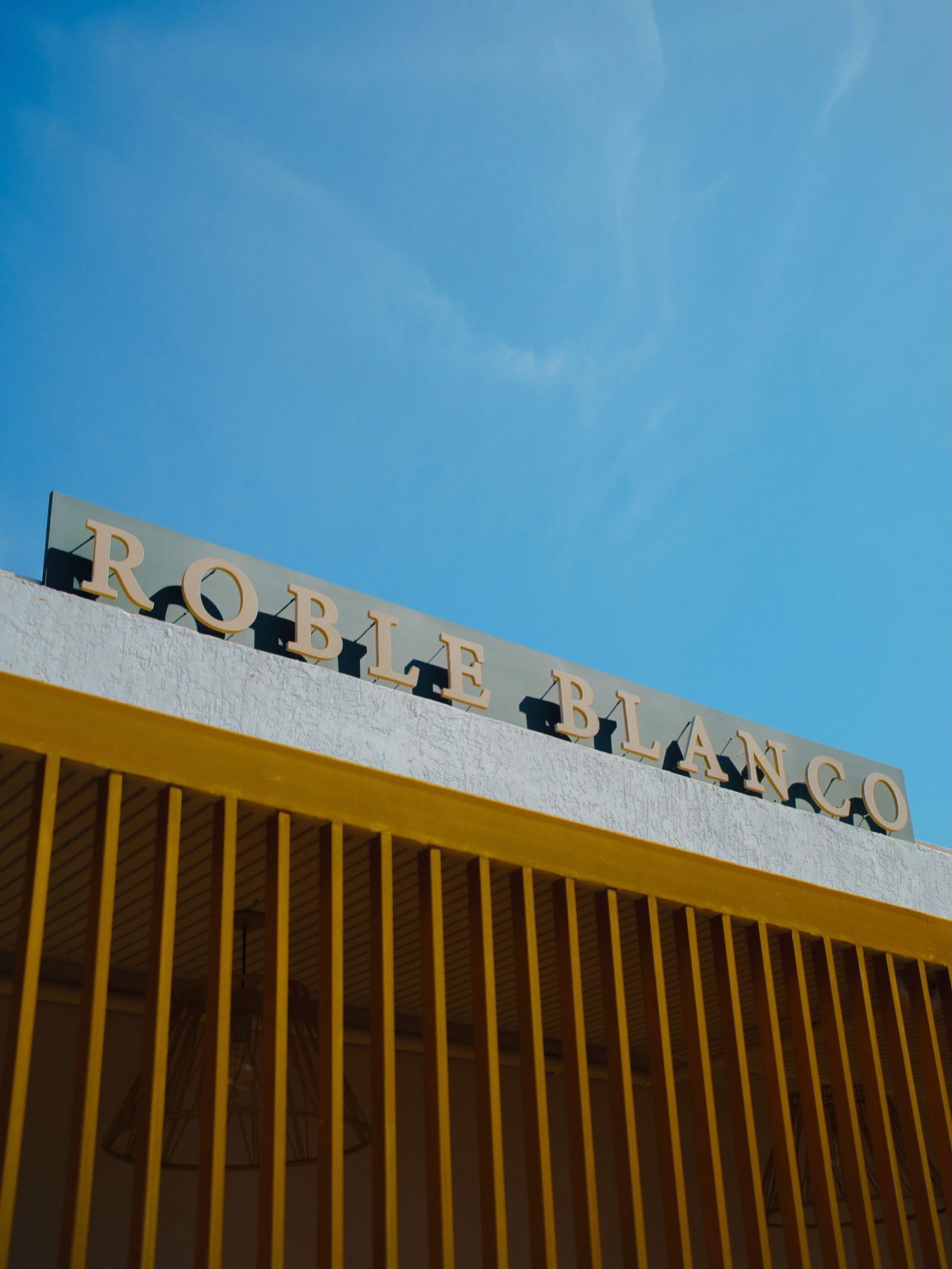 Roble Blanco storefront sign above a yellow slatted screen